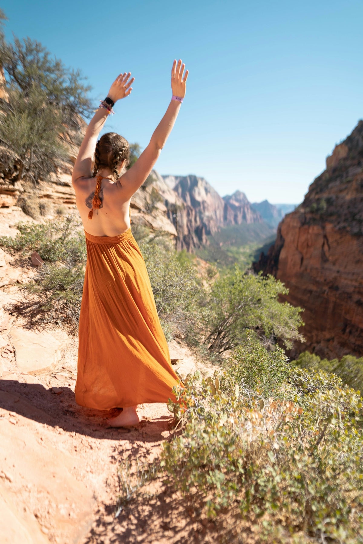 woman in orange dress standing on brown rock formation during daytime