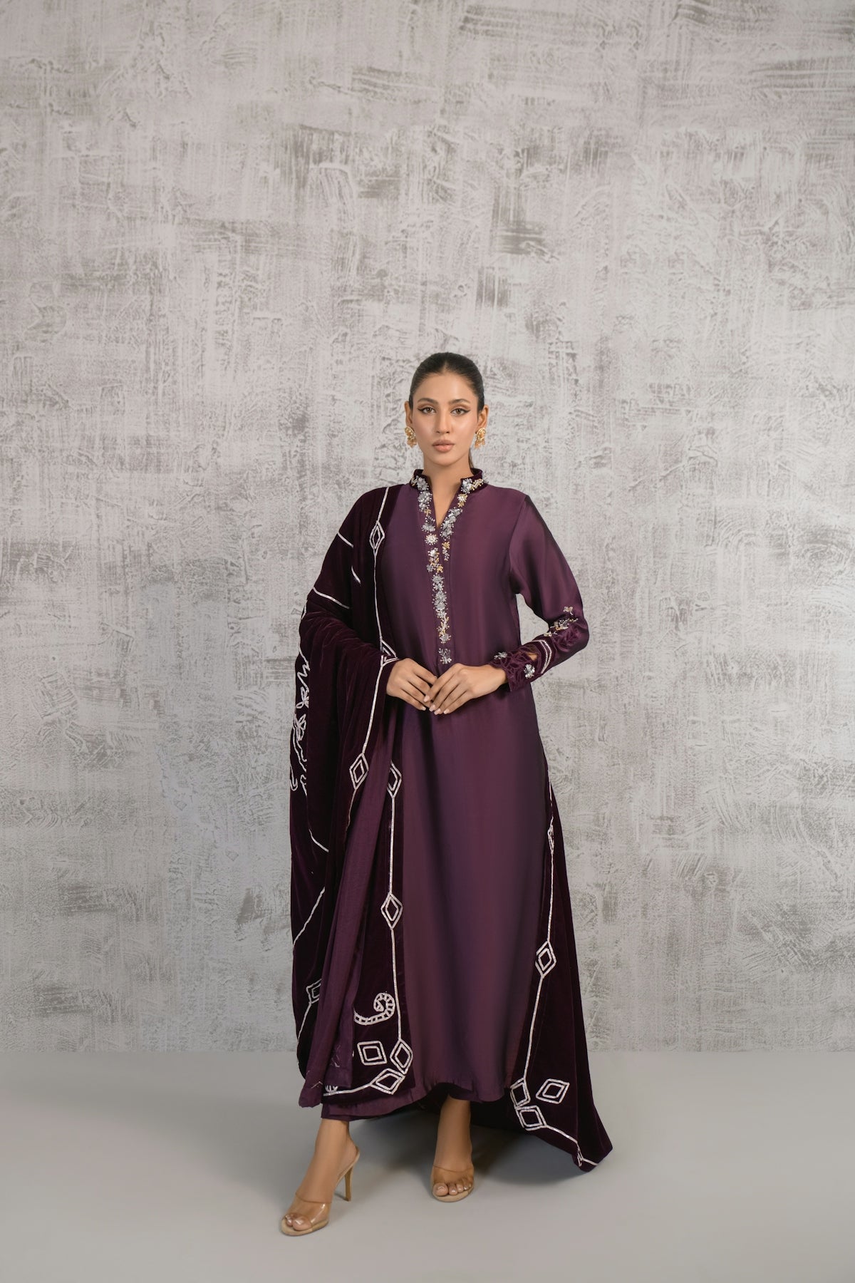 A woman in a purple dress standing in front of a wall