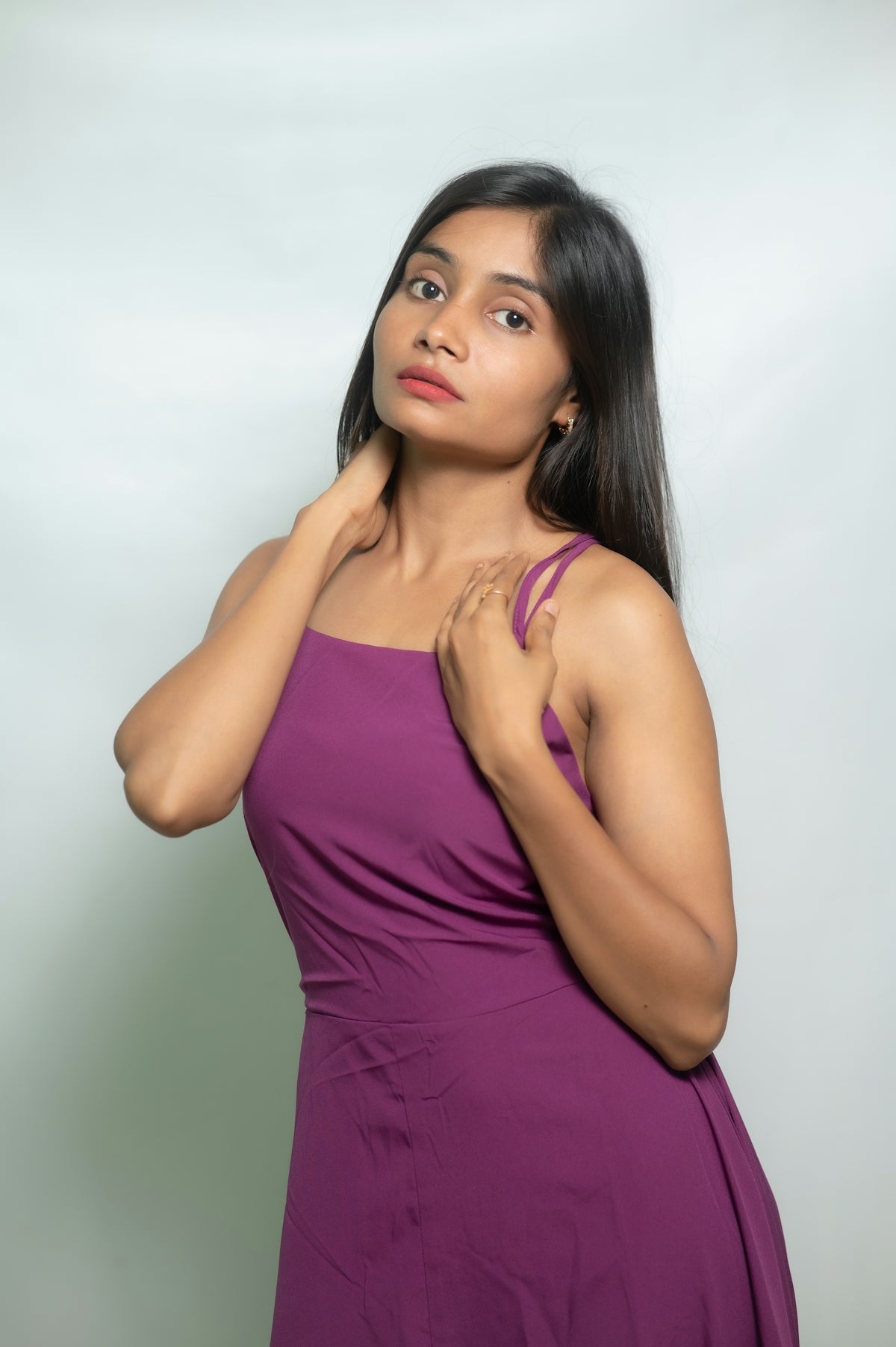A woman poses in a purple dress.