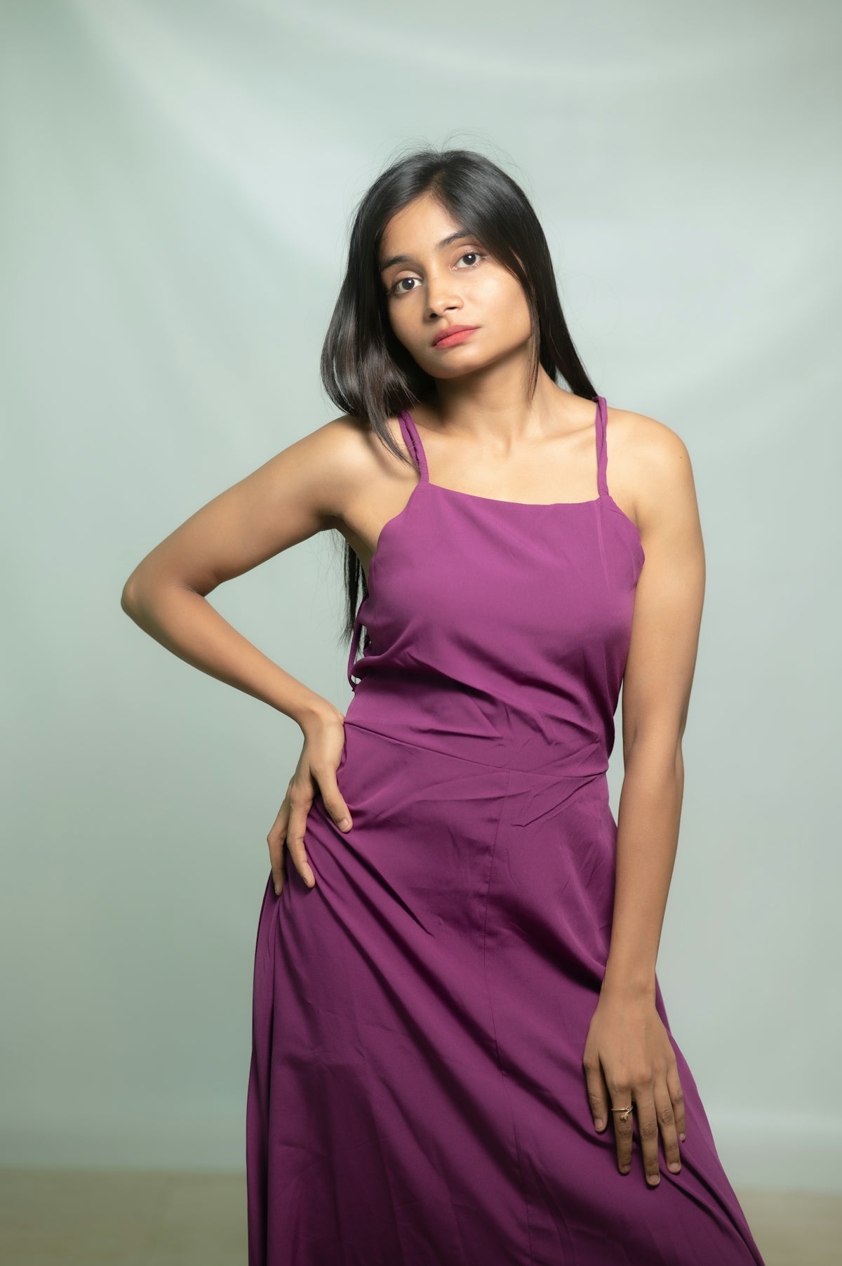 A woman poses in a purple dress.