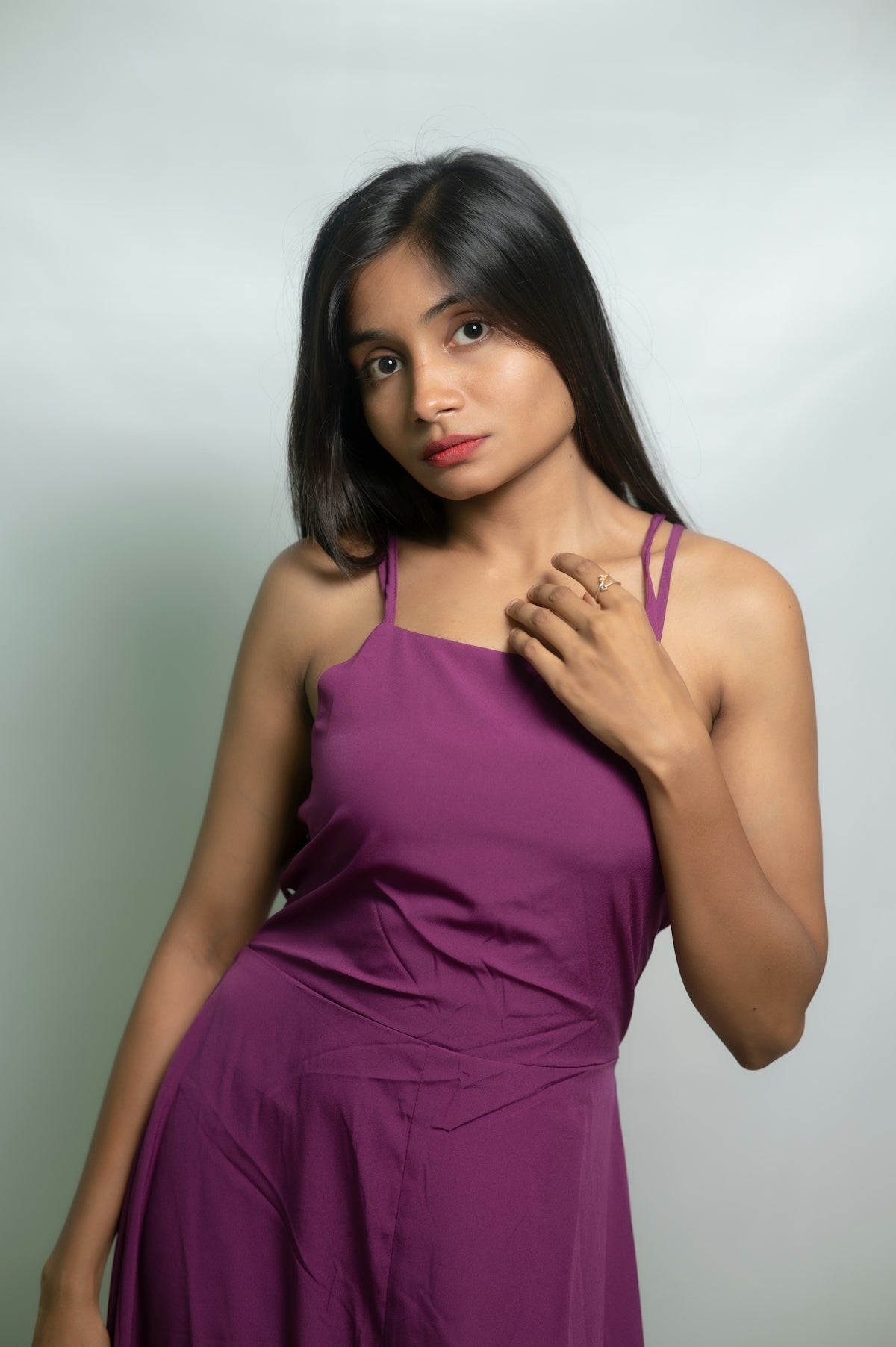 A woman poses in a purple dress.