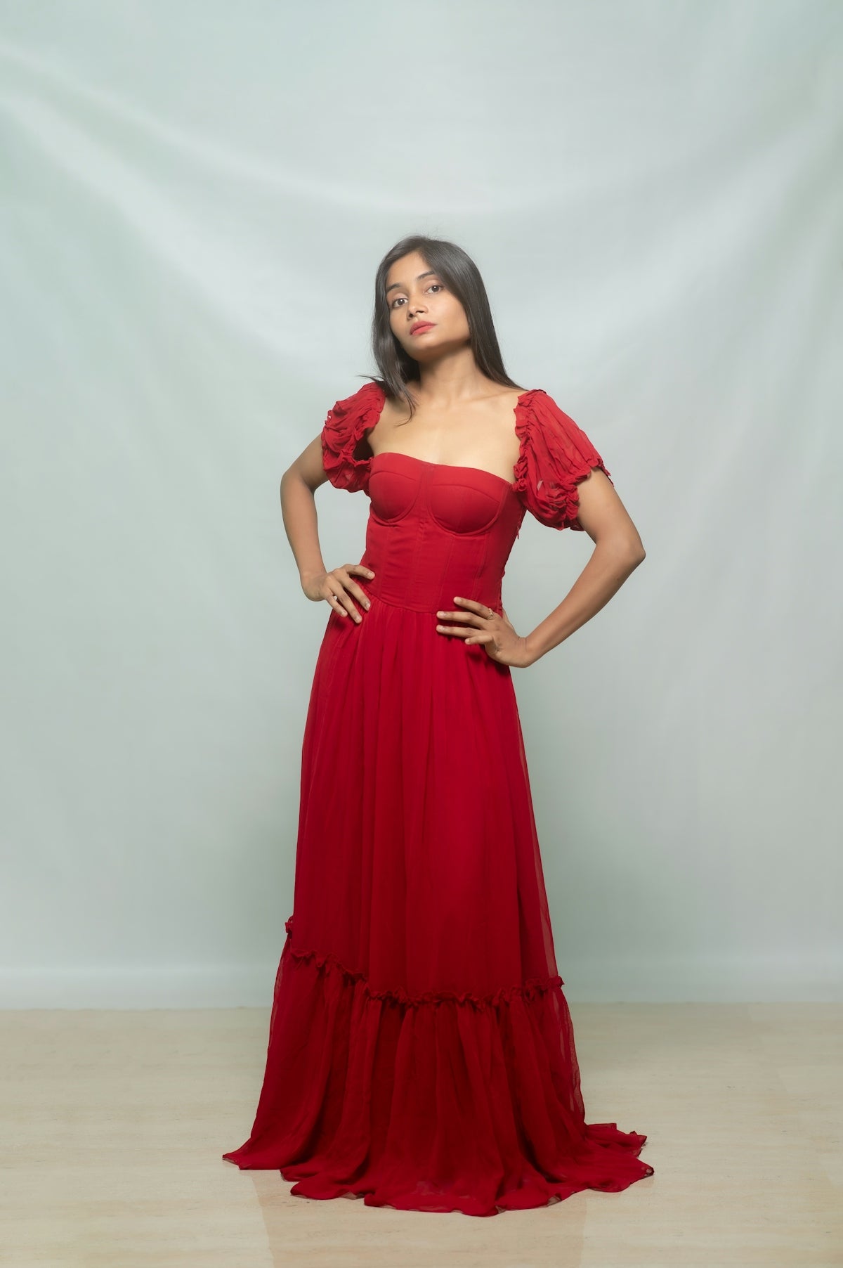 A woman poses in an elegant red dress.