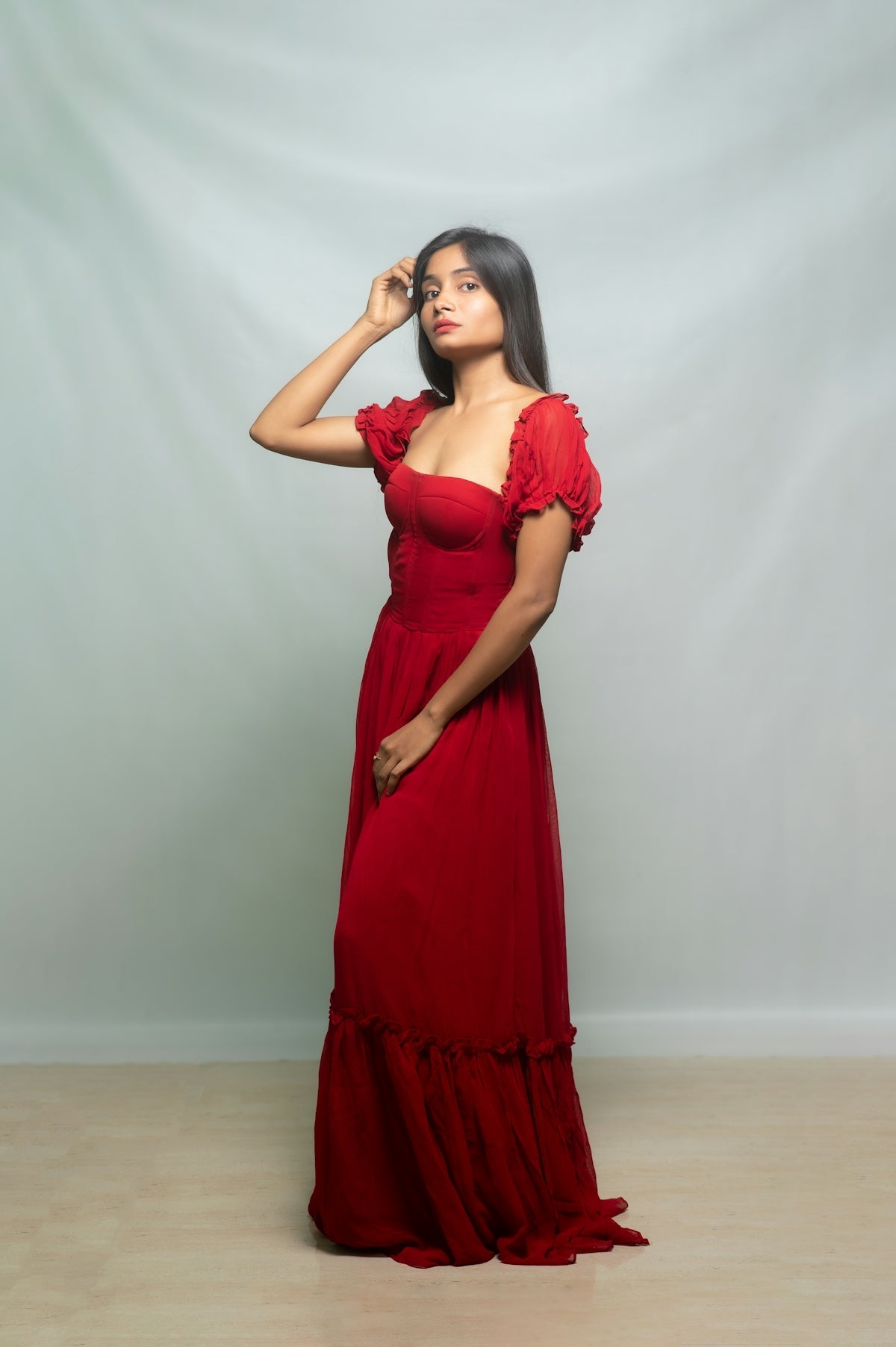 Woman poses gracefully in a long red dress.