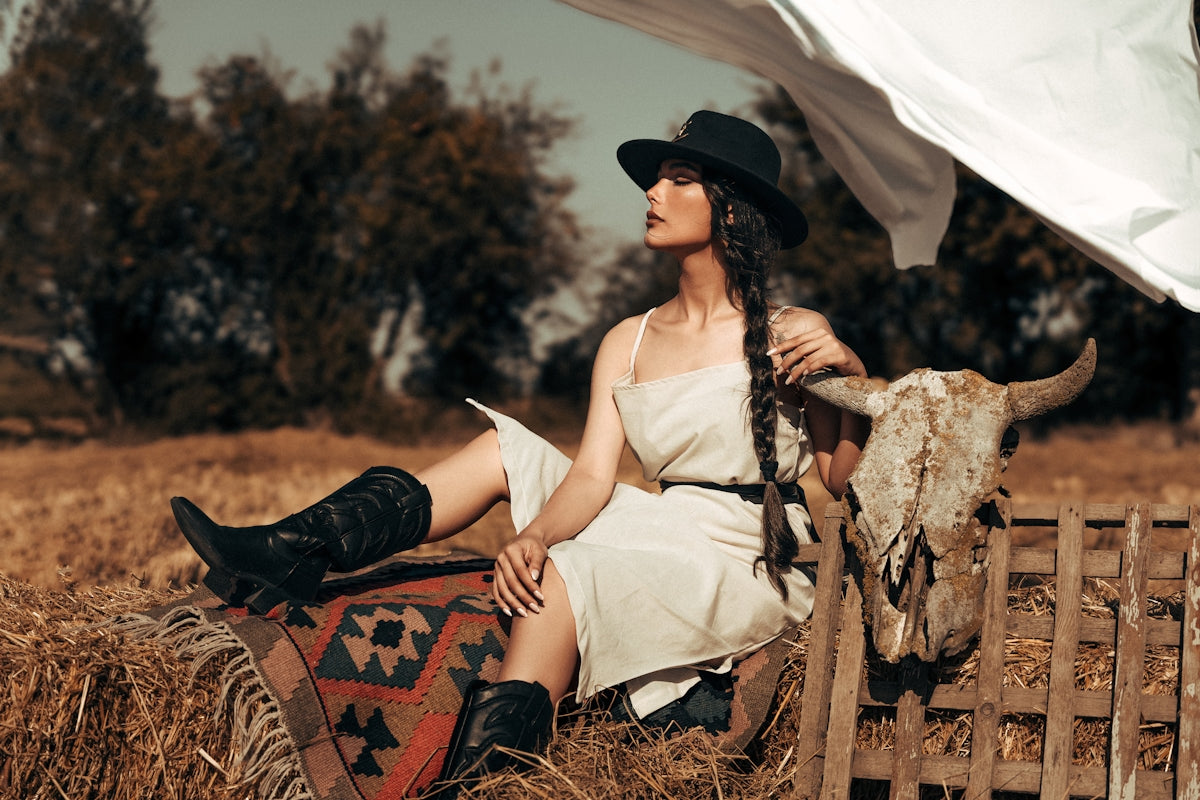Woman in cowboy hat and dress on hay bale