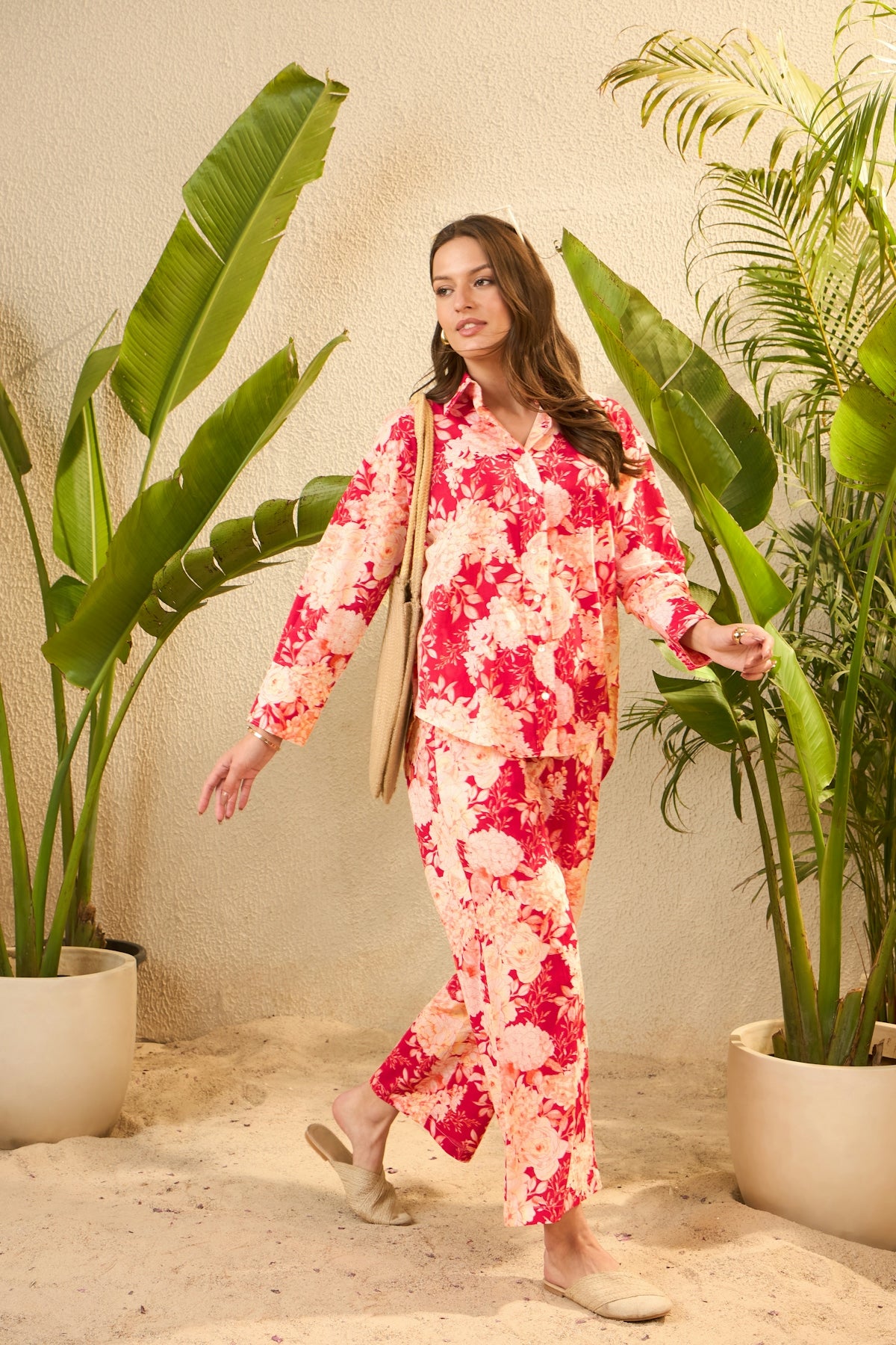 Woman in floral pajamas walking among tropical plants.